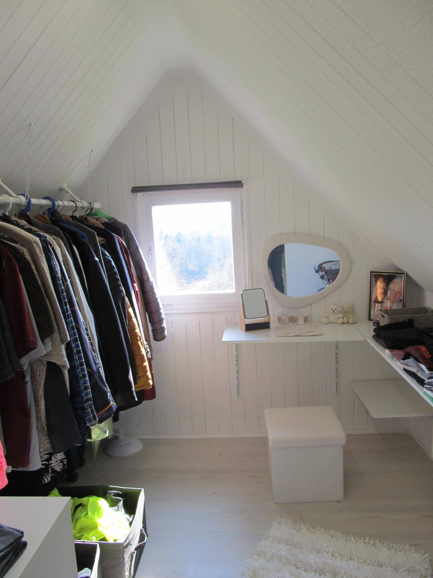 Begehbarer Kleiderschrank im Dachgeschoss mit Fenster und Ablageflächen.