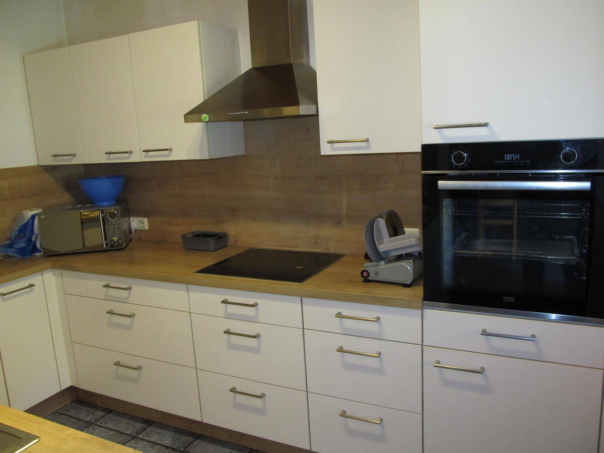 Moderne Einbauküche mit weißen Fronten, Holzoptik-Arbeitsplatten und integriertem Backofen.
