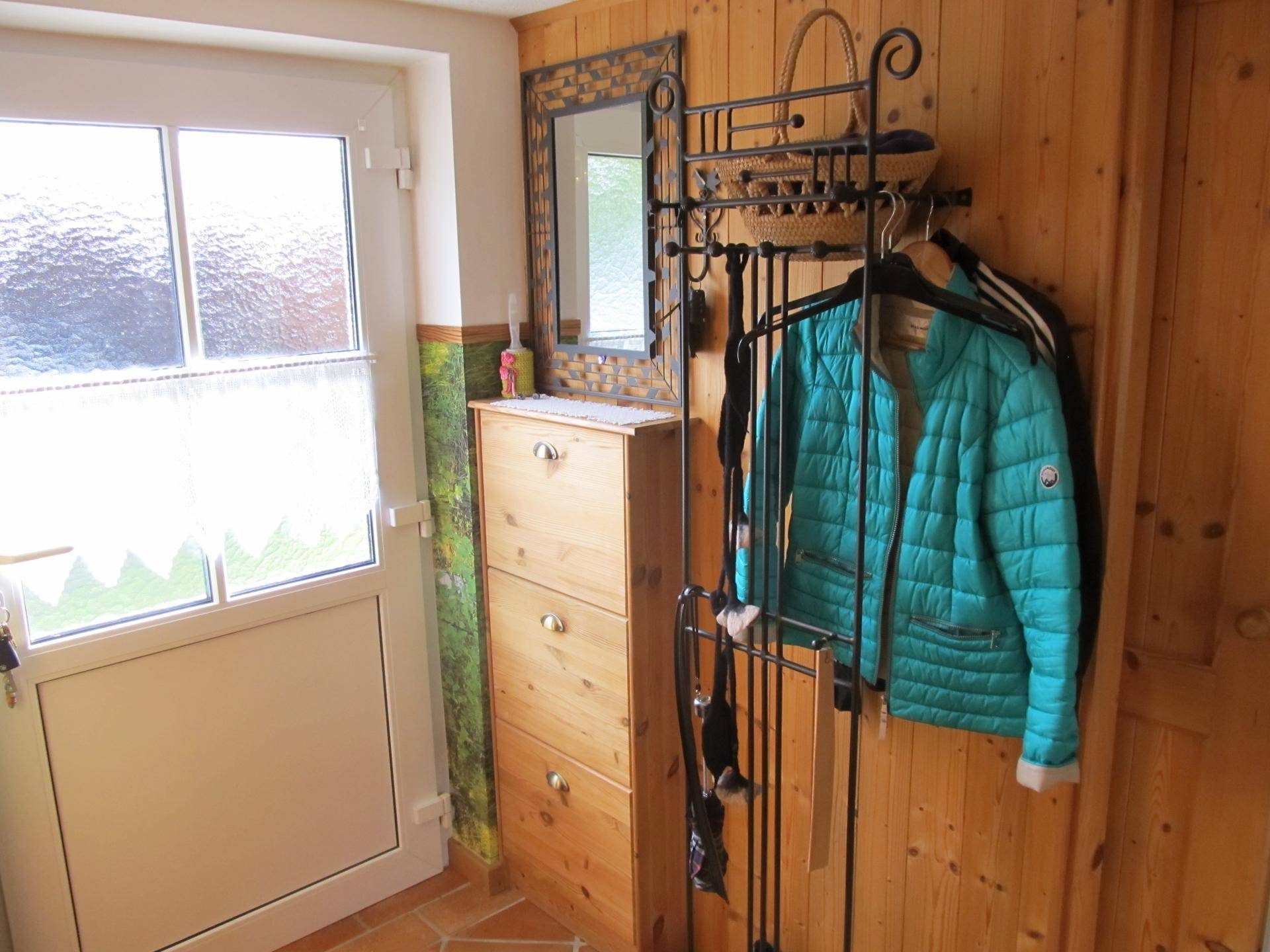 Eingangsbereich mit Holzvertäfelung, Schuhschrank und Garderobe.