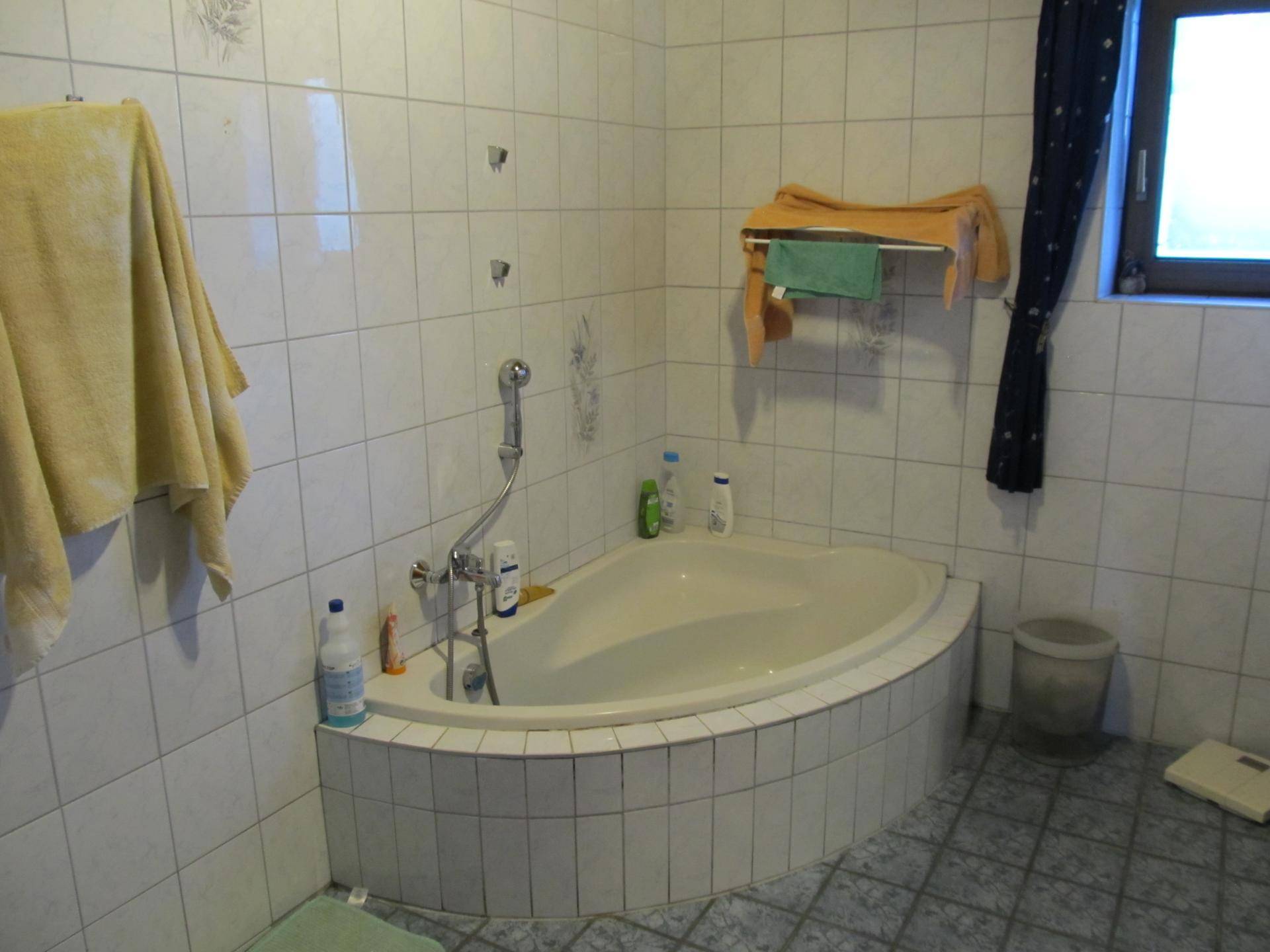 Badezimmer mit Eckbadewanne und weißen Fliesen, funktional und hell.