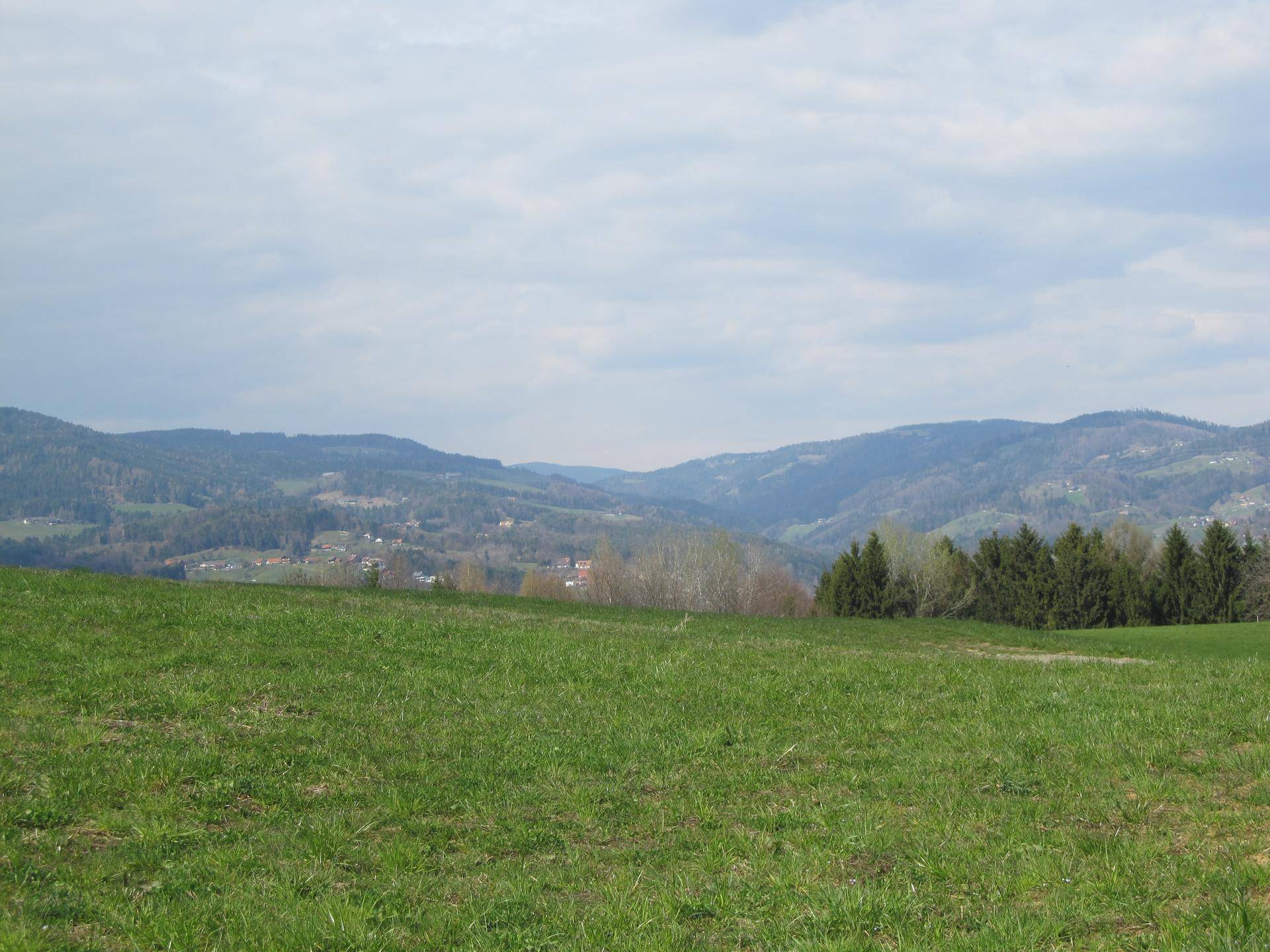 Panoramablick auf sanfte Hügel und Täler in ländlicher Umgebung.