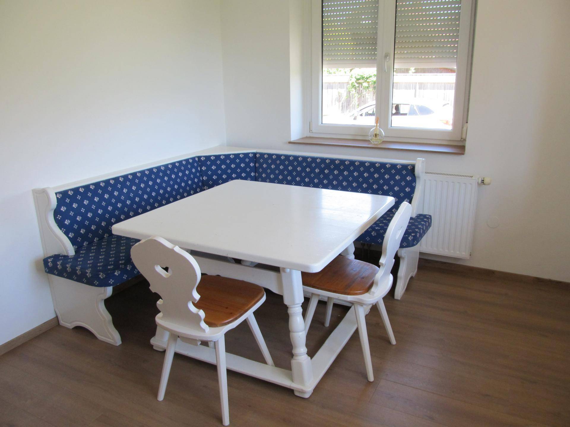 Gemütlicher Essbereich mit traditioneller Eckbank, Esstisch und Fenster mit Rollladen.