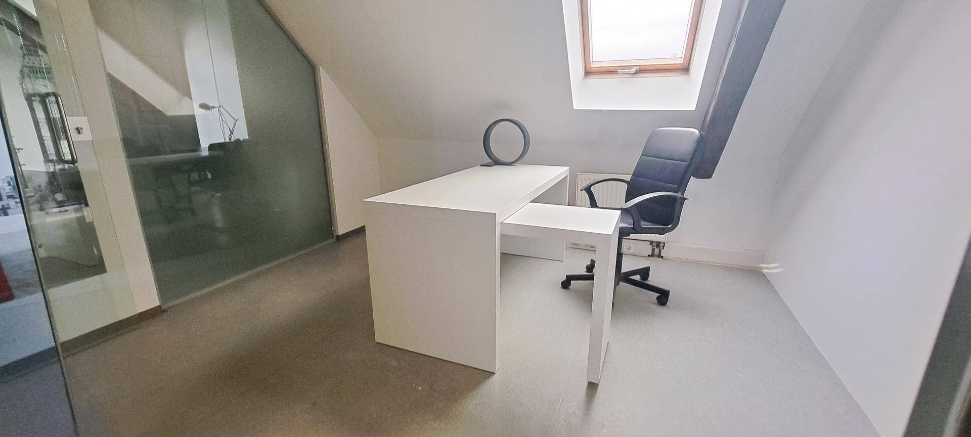 Geräumiges Dachgeschossbüro mit modernem Schreibtisch, Bürostuhl und viel Tageslicht durch das Dachfenster.