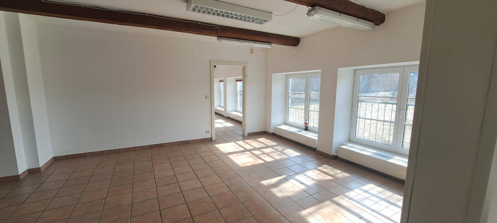 Heller Büroraum mit Terrakottafliesen, sichtbaren Holzbalken und natürlichem Lichteinfall.