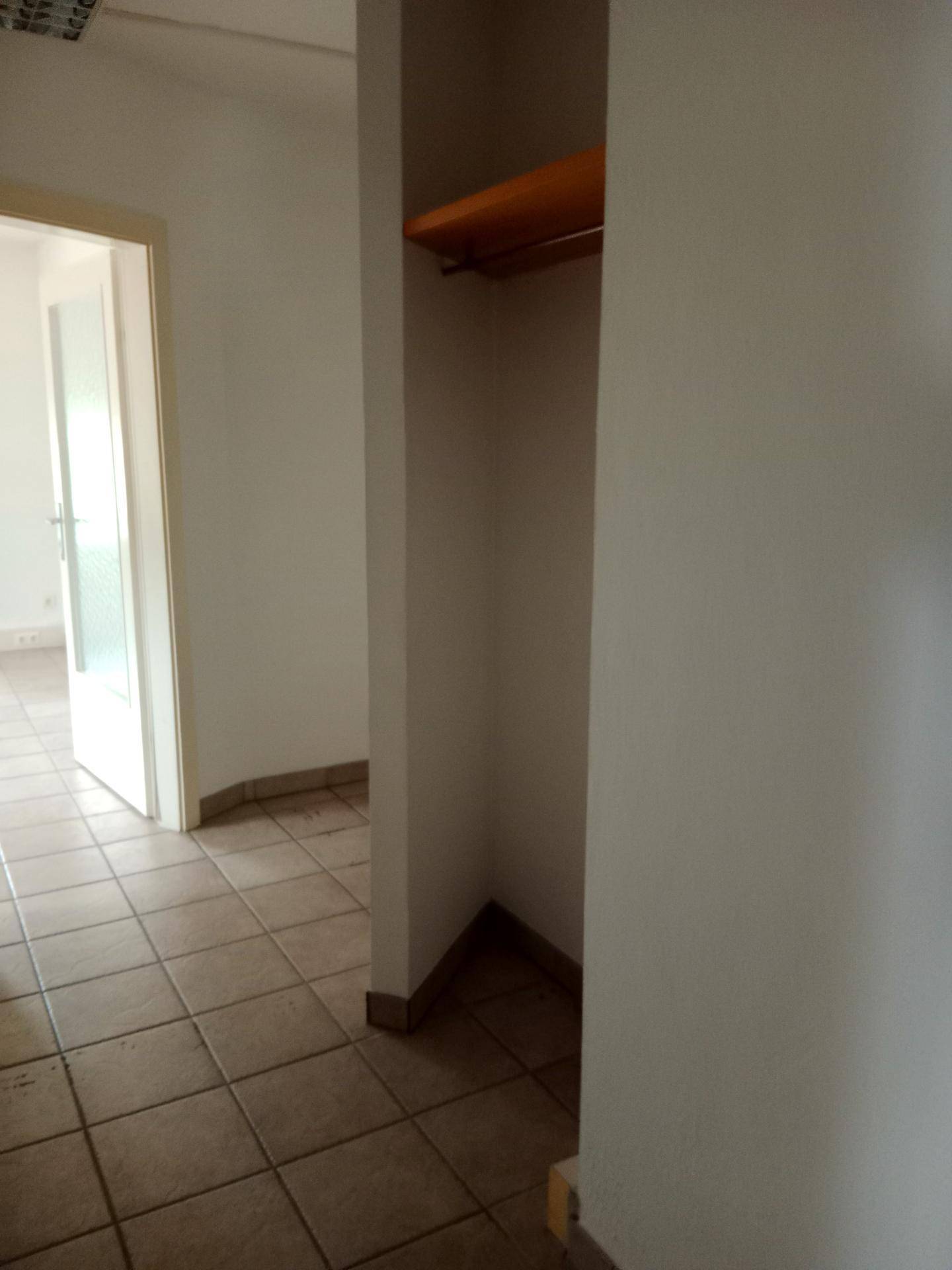 Kleiner Abstellraum oder Nische mit Fliesenboden und einer einfachen Holzablage, ideal für Lagerung.