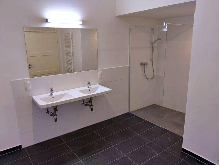 Modernes Badezimmer mit Doppelwaschbecken, großer Spiegelfläche und begehbarer Dusche.