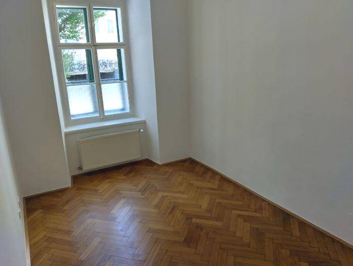 Heller Raum mit Fischgrätparkettboden und Fenster, bietet eine angenehme Wohnatmosphäre.