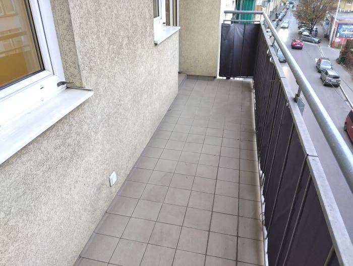 Geräumiger Balkon mit Fliesenboden und seitlichem Blick auf die Straße, ideal für frische Luft.