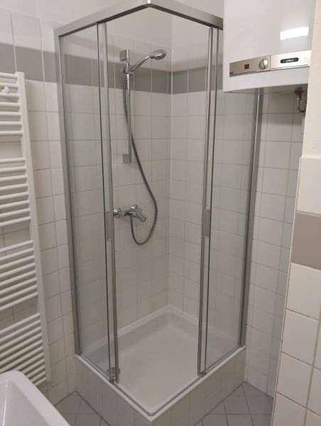Badezimmer mit Duschkabine, Fliesenwänden und beheiztem Handtuchhalter.