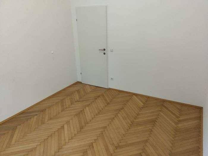 Heller Raum mit klassischem Fischgrätparkettboden und weißer Tür, vielseitig einsetzbar.