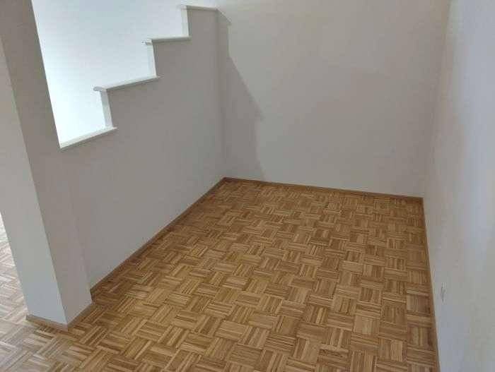 Ruhiger Eckbereich eines Wohnraums mit Parkettboden und weißen Wänden.