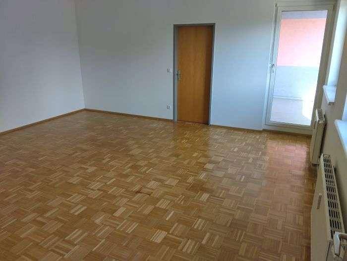 Geräumiges Wohnzimmer mit klassischem Parkettboden und weiß gestrichenen Wänden.