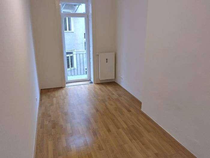 Helles Zimmer mit Holzplankenboden und Zugang zu einem französischen Balkon, ideal für viel Tageslicht.