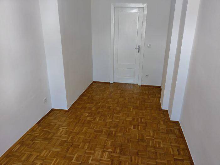 Heller Flur mit Würfelparkett und einer weißen Tür, ideal für den Eingangsbereich.