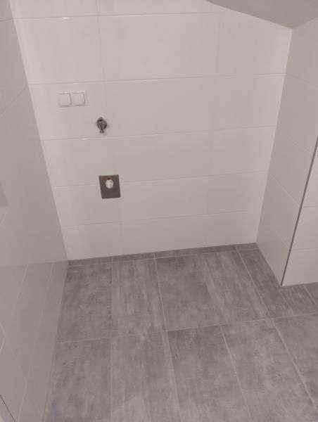 Wandbereich im Badezimmer mit Vorinstallation für ein wandhängendes WC und Fliesenboden.