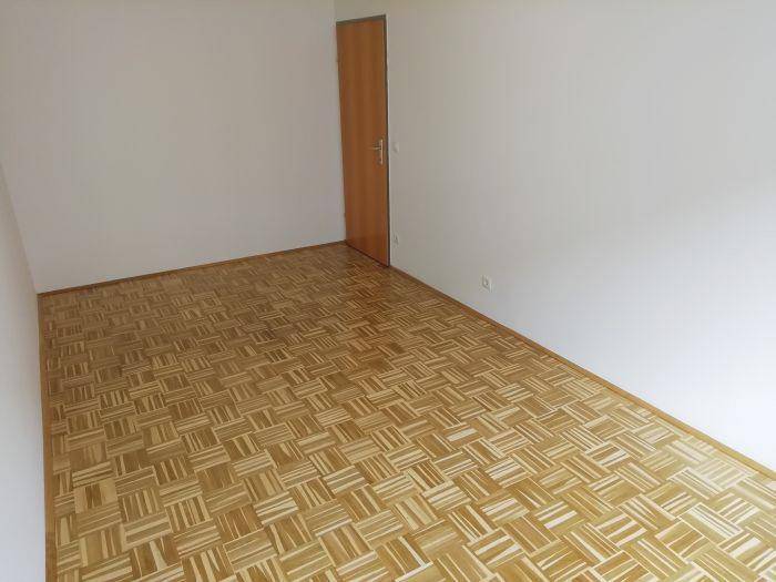 Geräumiges Schlafzimmer mit Parkettboden und Holztür, ideal für erholsame Nächte.