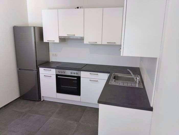 Kompakte Küche mit weißen Oberschränken, Spüle und Kühlschrank.