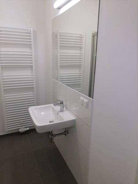 Helles Badezimmer mit Einzelwaschbecken, großem Spiegel und praktischem Handtuchheizkörper.