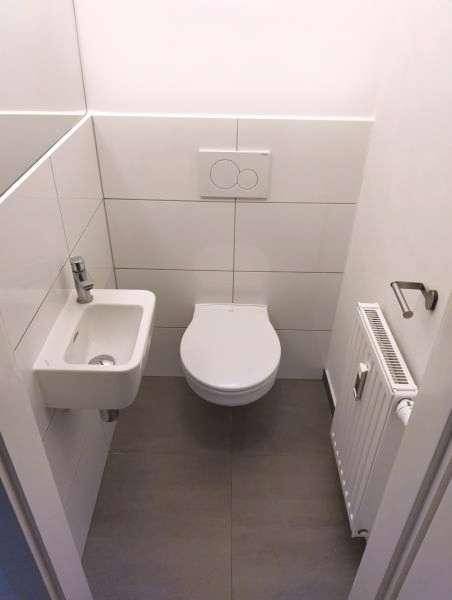 Kleines Gäste-WC mit wandhängender Toilette, Waschbecken und Heizkörper, modern und platzsparend.