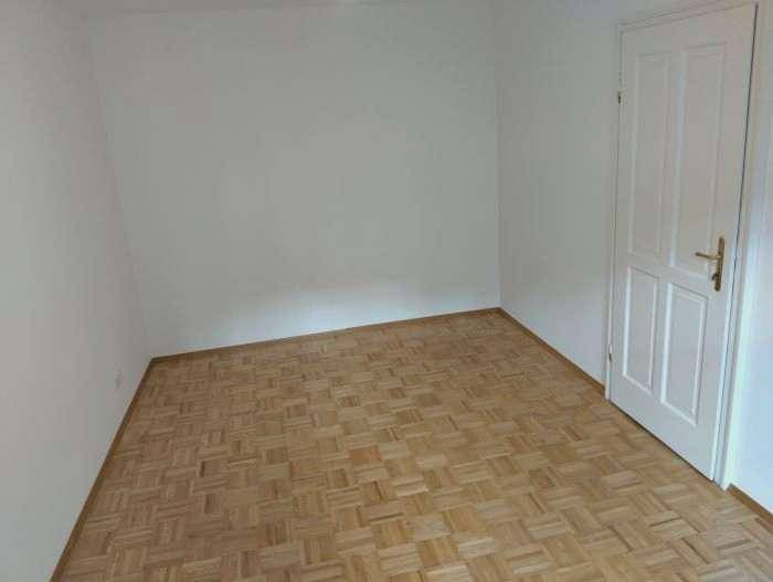 Schlichter Raum mit Parkettboden und weißer Tür, ideal für ein Schlaf- oder Arbeitszimmer.