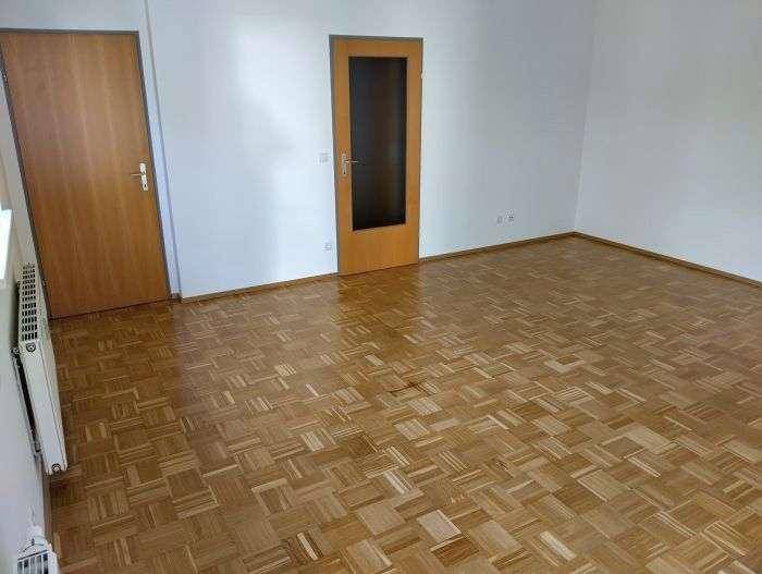 Heller Wohnraum mit Parkettboden und zwei Holztüren, eine davon mit Glaseinsatz.