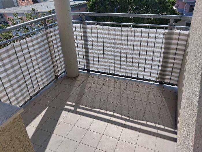 Sonniger Balkon mit Fliesenboden und Sichtschutz für private Stunden im Freien.