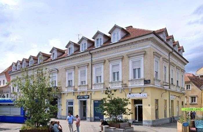 Historisches Gebäude mit klassischer Fassade, vielen Fenstern und Geschäften im Erdgeschoss.