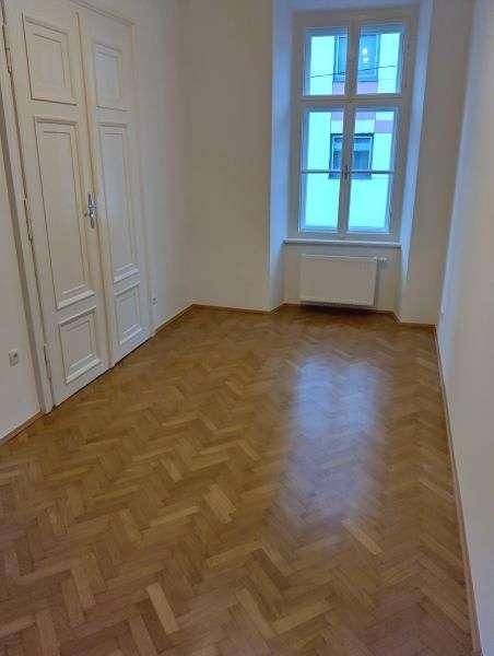 Helles Zimmer mit Fischgrätparkett, Fenster und einem praktischen Einbauschrank.