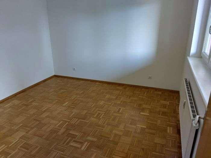 Leeres Schlafzimmer mit Parkettboden und weiß gestrichenen Wänden.