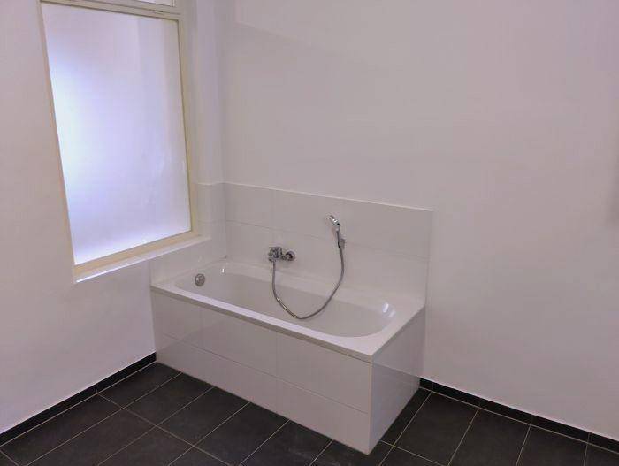 Helles Badezimmer mit eingebauter Badewanne und einem Fenster für natürliches Licht.
