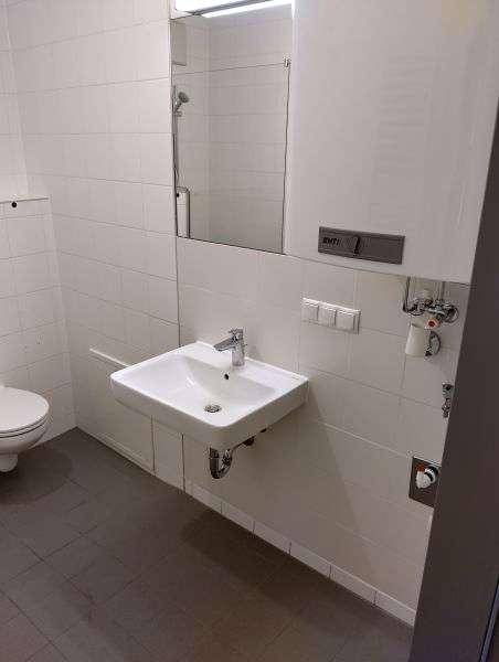 Badezimmer mit modernem Waschbecken, Spiegel und weißen Fliesen.