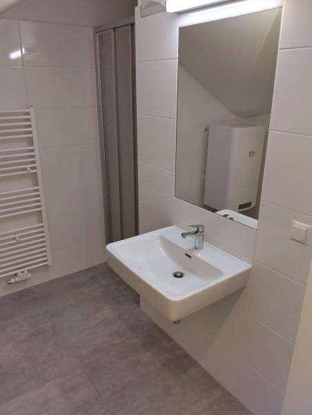 Modernes Badezimmer mit Waschbecken, Spiegel, Handtuchheizkörper und gefliesten Wänden.