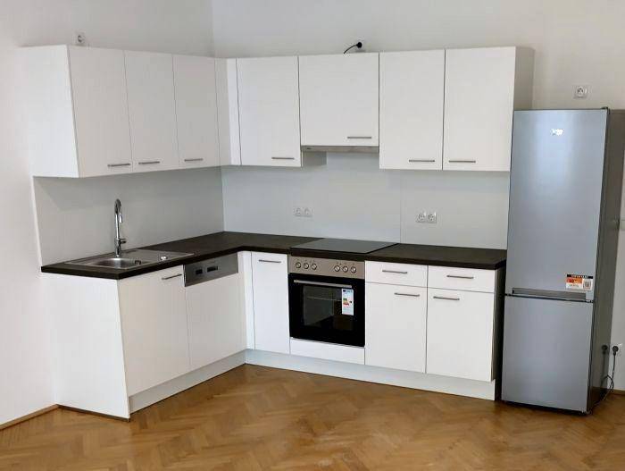 Moderne Einbauküche in Weiß mit dunkler Arbeitsplatte, Herd und Kühlschrank.