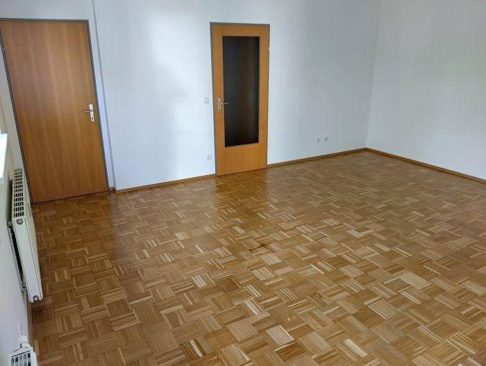 Heller Raum mit klassischem Parkettboden und einer Holztür, bereit für neue Bewohner.