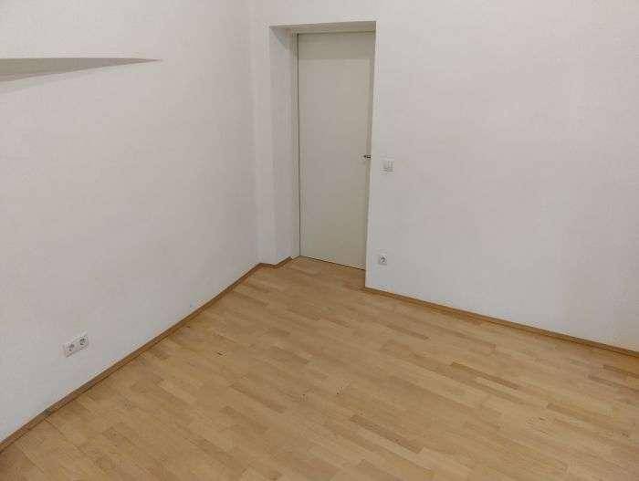 Leerer Raum mit hellem Holzfußboden und weißer Tür, bereit zur individuellen Gestaltung.