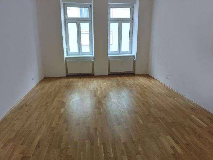 Helles Zimmer mit neuem Holzplankenboden und zwei Fenstern, bereit zum Einzug.