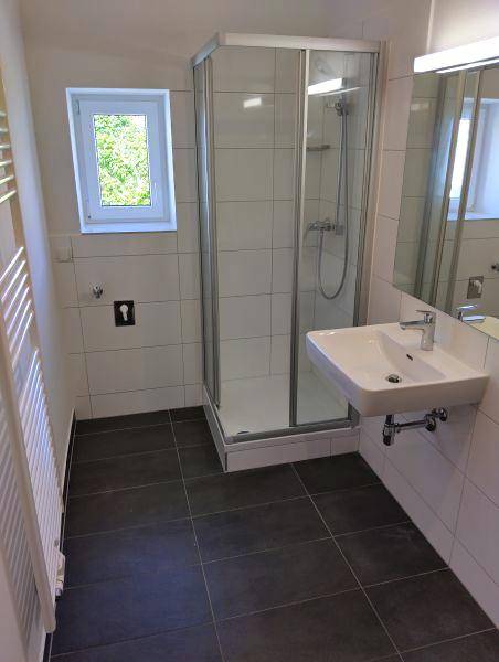 Modernes Badezimmer mit Duschkabine, Waschbecken, Spiegelschrank und Fenster.