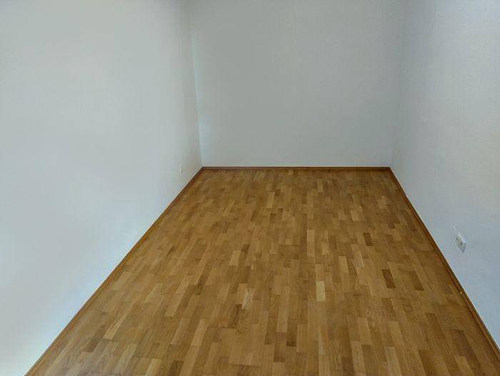 Schlichter Raum mit Parkettboden und weißen Wänden, ideal für individuelle Gestaltung und Nutzung.