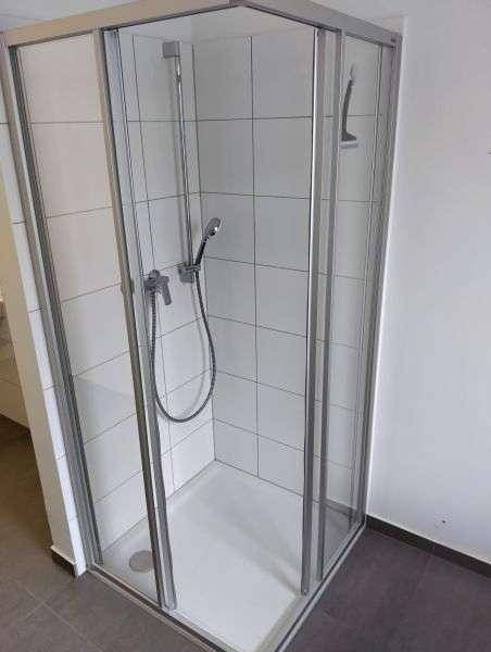 Modernes Badezimmer mit einer Duschkabine und weißen Fliesen, funktional und sauber.