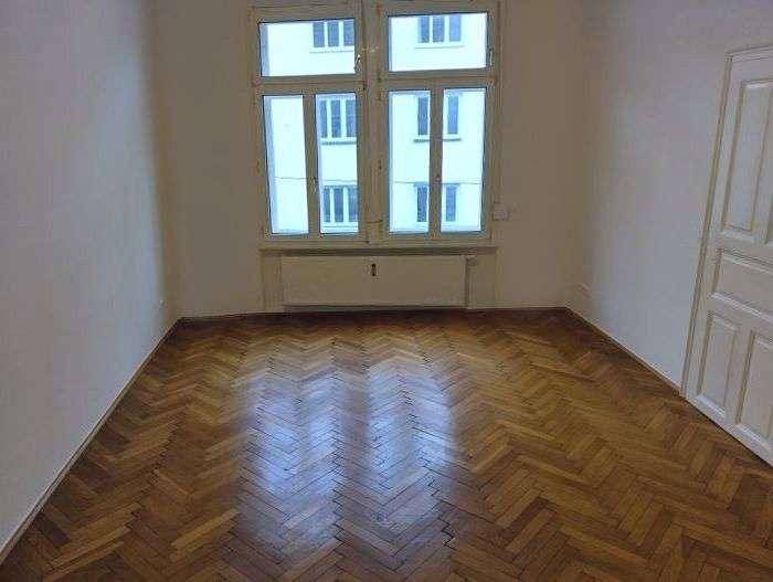 Helles, leeres Zimmer mit klassischem Fischgrätparkettboden und großen Fenstern, ideal für individuelle Gestaltung.