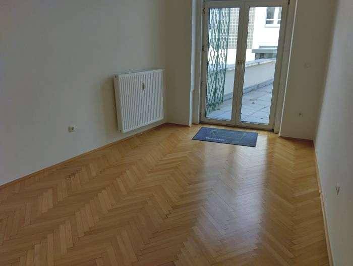 Heller Raum mit Parkettboden und direktem Zugang zu einer Außenterrasse, bietet viel Tageslicht.