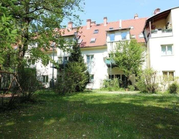Gepflegter Gemeinschaftsgarten mit Rasenfläche und Bäumen, umgeben von der Wohnanlage.