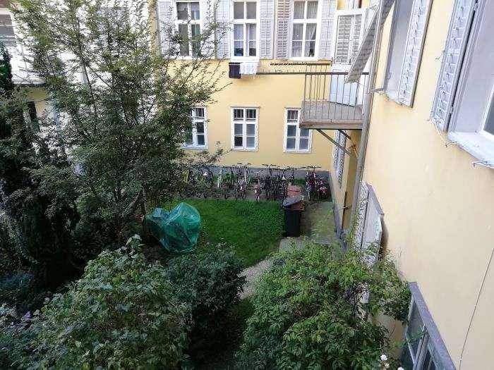 Grüner Innenhofgarten mit Rasenfläche, Bäumen und Fahrradabstellplätzen, ruhige Umgebung.