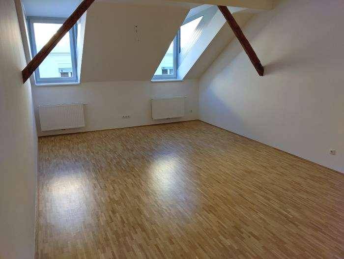Geräumiges Schlafzimmer im Dachgeschoss mit Holzbalken, Parkettboden und zwei Fenstern.