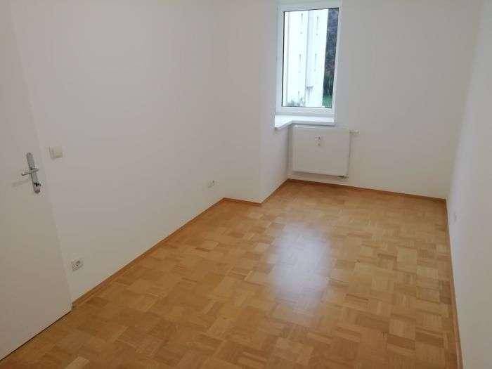 Ruhiges Schlafzimmer mit Parkettboden und einem Fenster, das für angenehmes Tageslicht sorgt.