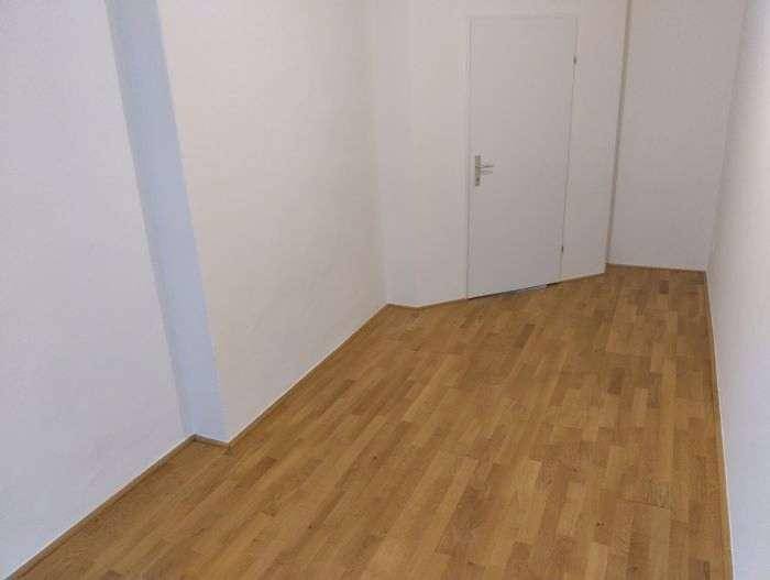 Geräumiges Zimmer mit hellem Holzplankenboden und einer modernen weißen Tür, bietet vielseitige Nutzungsmöglichkeiten.