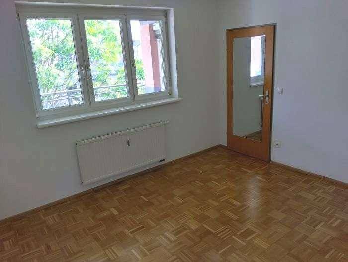 Schlafzimmer mit Parkettboden, großem Fenster und viel Tageslicht.