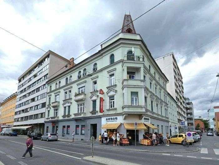 Historisches Eckgebäude in der Stadt mit Geschäften im Erdgeschoss und Wohnungen darüber.