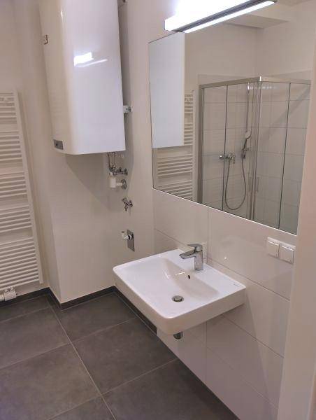 Badezimmer mit modernem Waschbecken, Spiegelschrank und Handtuchheizkörper.
