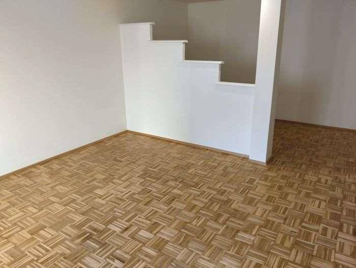 Heller Wohnbereich mit Parkettboden und einer modernen Treppe, die zu einer weiteren Ebene führt.